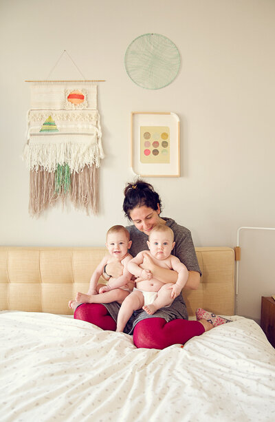 mom and twin baby girls sitting on bed