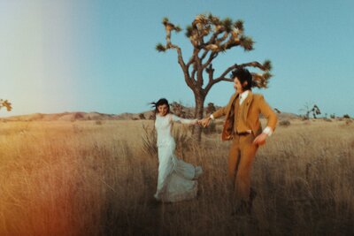 couple holding hands and running through Joshua Tree