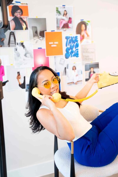Behind-the-scenes look at a brand photographer in her styled studio with branded visuals on the wall