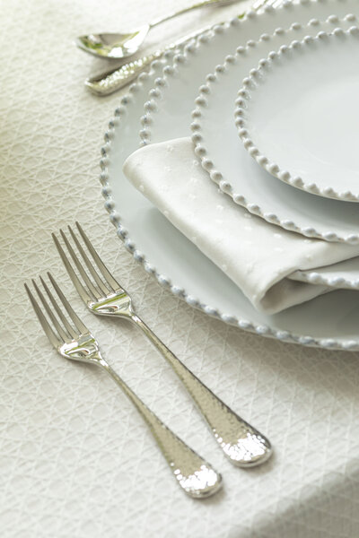 Elegant white pearl dishware and silver flatware set for a wedding reception
