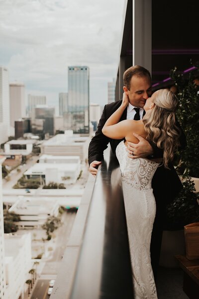 Bride and groom kissing at a rooftop bar overlooking the downtown Tampa skyline after their intimate wedding at Rooftop 220