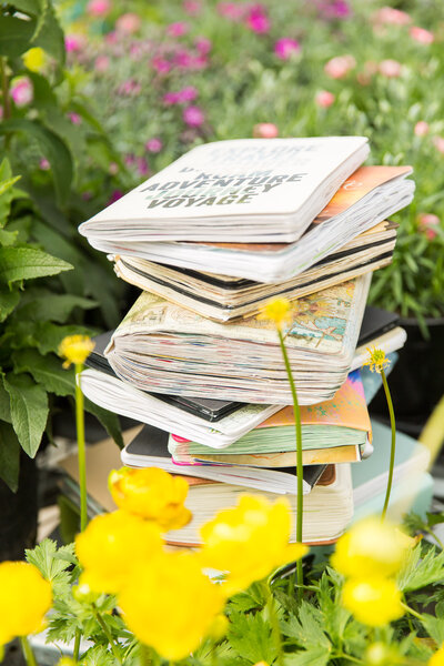 A pile of travel journals in a field of flowers