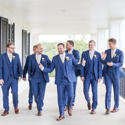A groom and his groomsmen pose on the balcony outside the groom's suite.