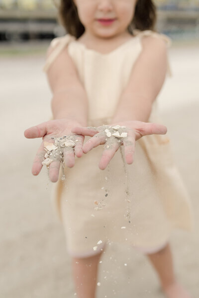 Little girl plays with sand and seashells in Wildwood, NJ