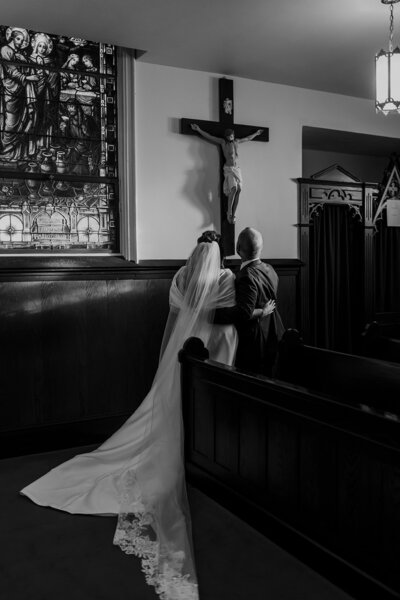 catholic bride and groom praying at the foot of Jesus