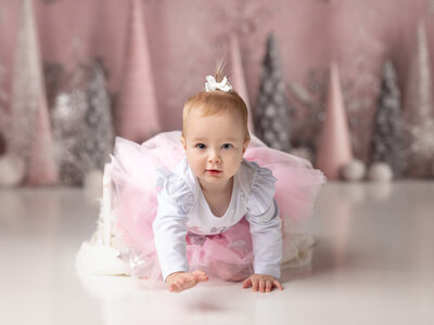 one year old girl in pink tutu crawling for one year cake smash