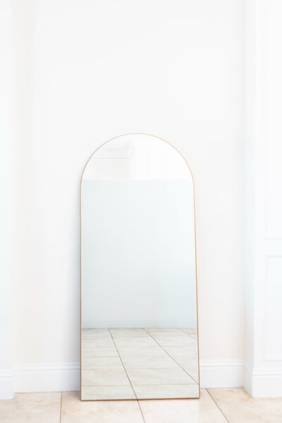 Gold arched mirror on stand