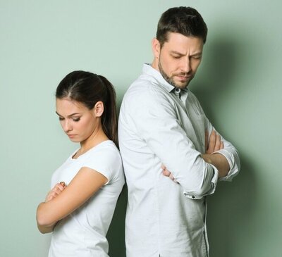 Upset couple standing back-to-back with arms crossed, illustrating a deep relationship conflict or communication breakdown needing marriage counseling.