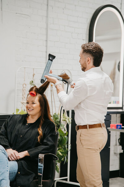 Salon Beau stylist using professional tools to create voluminous waves for a client.