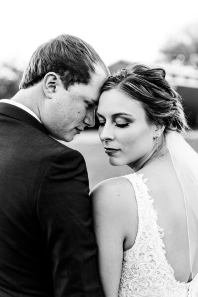 Close up of the bride and groom during sunset portraits of their temples touching as the bride looks down over her shoulder by Kansas City Wedding Photographer Sarah Riner Photography.