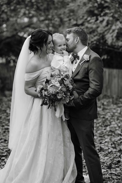 Couple with son share tender moment after tying the knot in candid wedding photography.