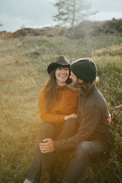 couple sitting in field and laughing