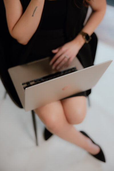 Image of a amy sitting in a chair with her laptop on her lap 