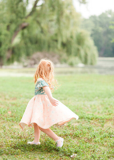 Mom playfully twirling daughter in a field of flowers in East Grand Rapids, candid Motherhood photography. 