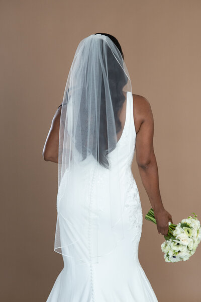Bride wearing a fingertip veil with ribbon edge and holding a white and black bouquet
