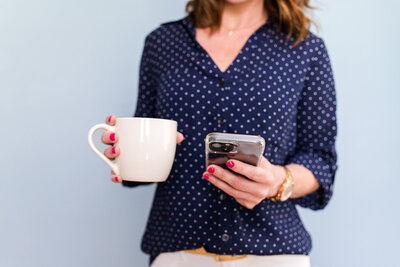 showit designer holding white coffee mug and iphone
