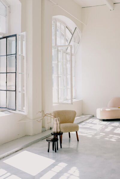 Light bright interior space with large opne windows and minimal furniture.