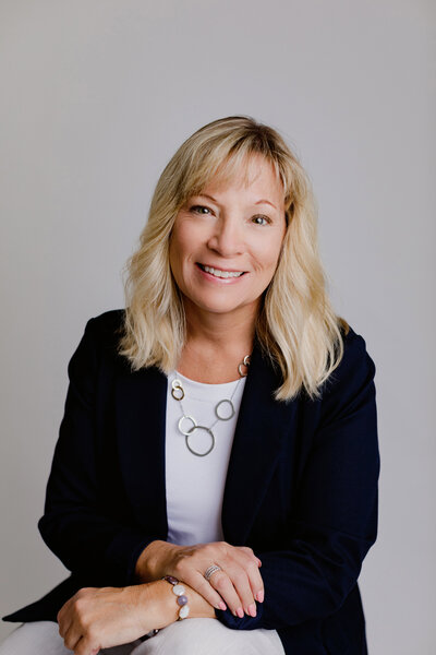 Professional woman smiles for headshot in black blazer