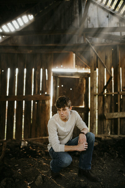 senior guy poses in barn during photo session