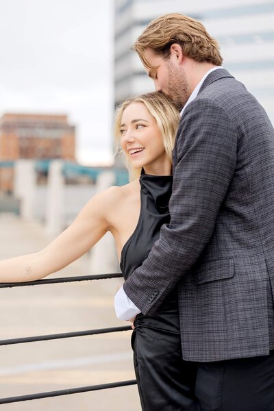 Man whispers into fiancee's ear during engagement photography session.