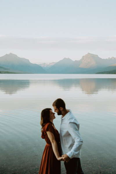 Man and woman standing next to Lake McDonald facing each other