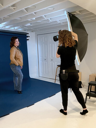 Behind-the-scenes photo of a branding and headshot photographer at work in a modern studio, capturing a professional portrait.