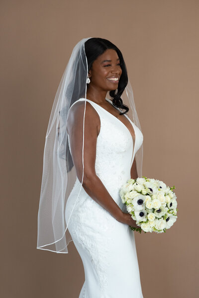 Bride wearing a fingertip length veil with small ribbon edge and holding a white and black bouquet