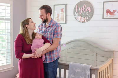 A Northern Virginia couple holding their newborn girl and standing in her nursery.