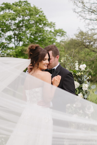 groom whispering into smiling bride's ear