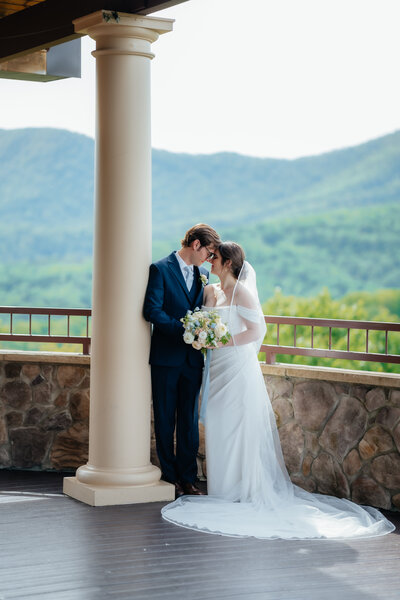 photo of bride and groom standing on a balcony outside with hills in the background taken by virginia elopement photographer
