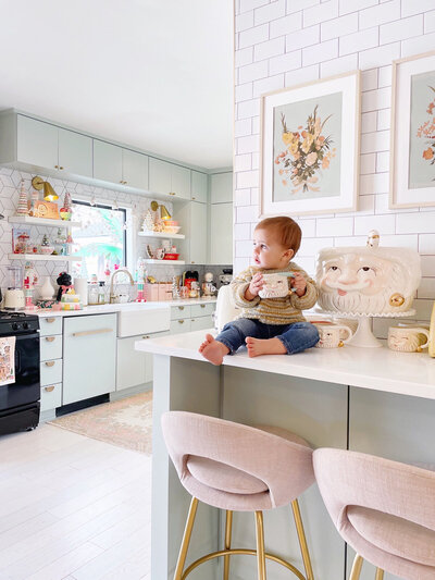 Baby sitting on the kitchen counter holding a mug