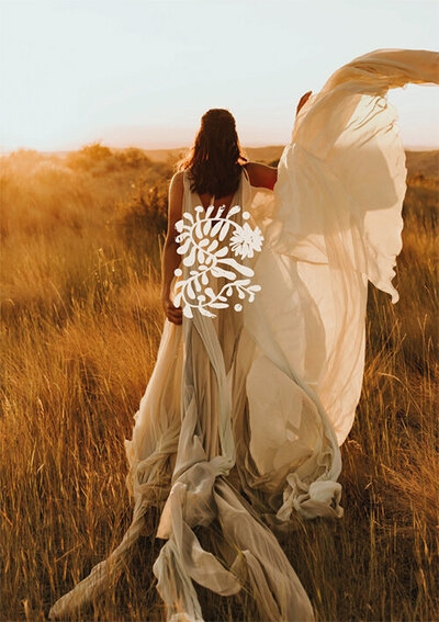 Logo icone végétal Elisa Demanet incrusté sur une photo représentant une femme de dos dans un champ de blé avec une longue robe blanche flottant dans les airs.