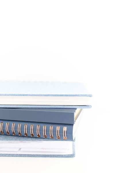 A neatly stacked set of blue and copper spiral-bound notebooks, symbolizing organization and planning, ideal for showcasing productivity and streamlined systems for business owners