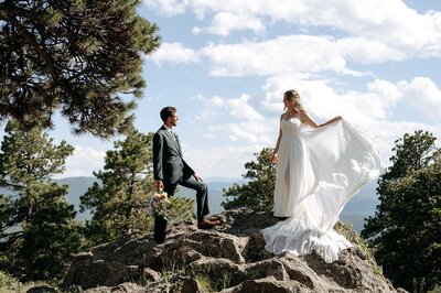 bride and groom standing on rocks