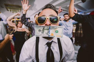 An indian wedding guest during the wedding reception with money in his mouth