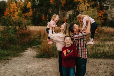 Greater Toronto Autumn mini Family Session at Kerncliff Park in Burlington holding up their daughters and son smiling at the camera.