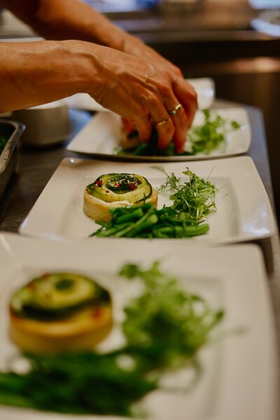 Vegan starters all lined up in a row in the kitchen being plated up by chef