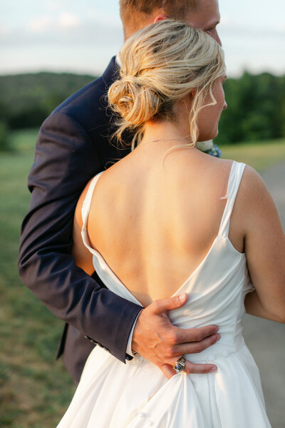 bride and groom embrace at sunset on golf course