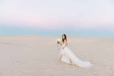 Bride walks across Las Vegas desert in wedding gown holding bridal bouquet