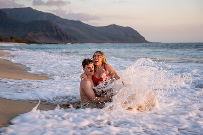 Hawaii engagement photography with couple playing in the ocean