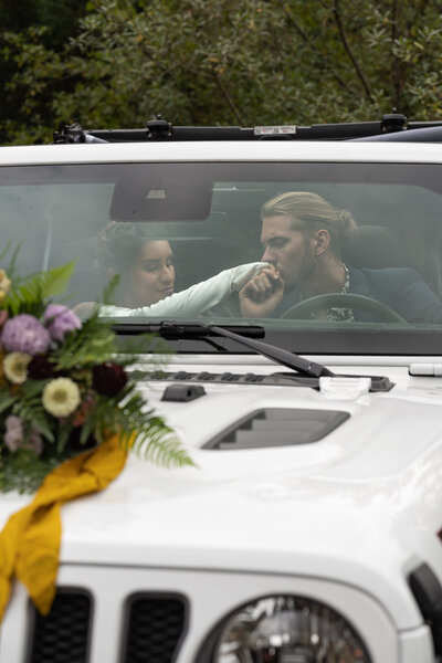 Two people in a car as one kisses the other's hand