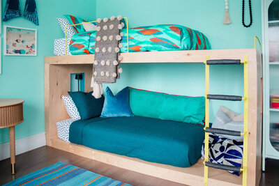 Bunk beds with blue blankets against light blue wall