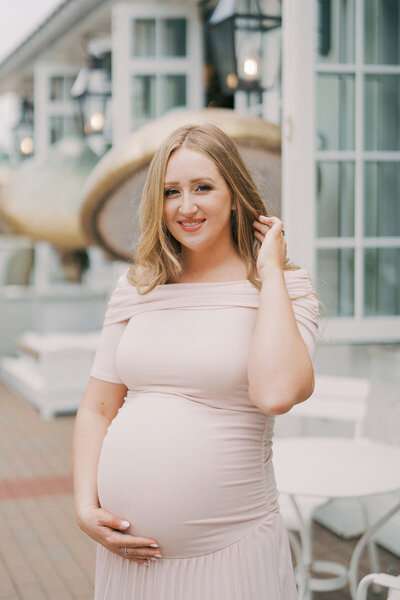 a pregnant woman smiling in a pink dress at her baby shower