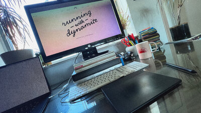 Computer monitor with Running With Dynamite logo on screen. Along with keyboard, laptop and tablet.