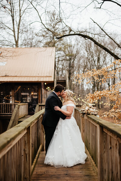 Wedding Couple kissing along a walkway at the mohican treehouse resort