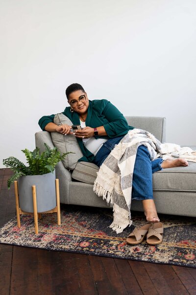 Career planning and strategy service expert sitting on a couch in a branded green outfit, working professionally on her phone.