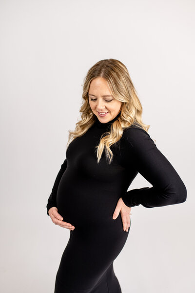A pregnant woman with one hand on her stomach and the other on her lower back.