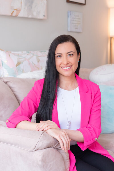 A woman smiling and standing in a strong but feminine pose for her headshot session.