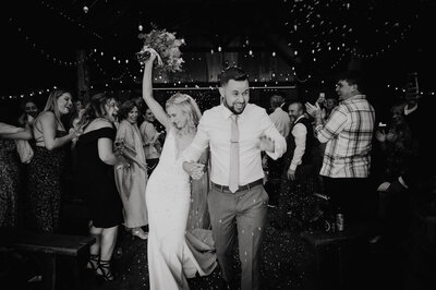 Happy couple exiting their wedding ceremony, bride has her bouquet raised in the air