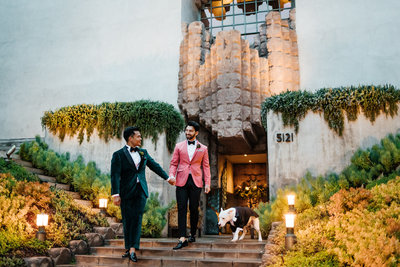 grooms holding hands in front of frank lloyd wright mansion in los angeles